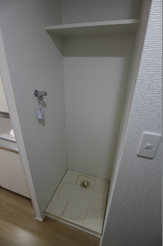 アクシオ小倉 玄関横の洗濯機置き場。洗剤などが置ける荷物場も設置済